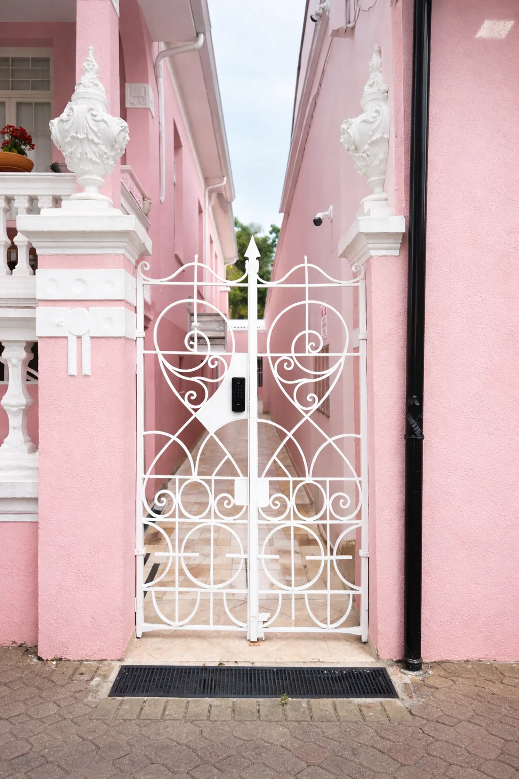 Portãozinho de ferro branco na fachada rosa