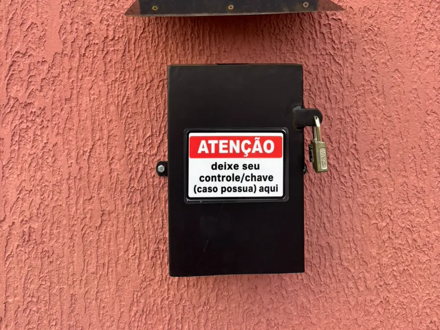Caixa preta na parede externa com o aviso para deixar o controle