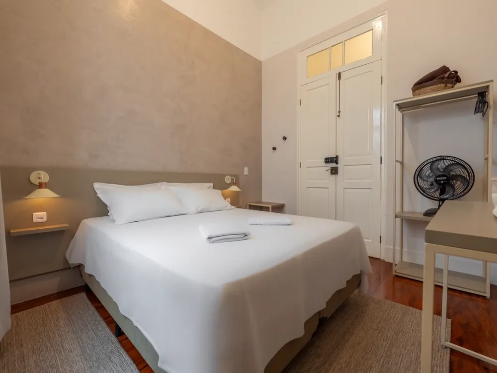 Quarto de casal com arandelas de cabeceira e porta francesa branca