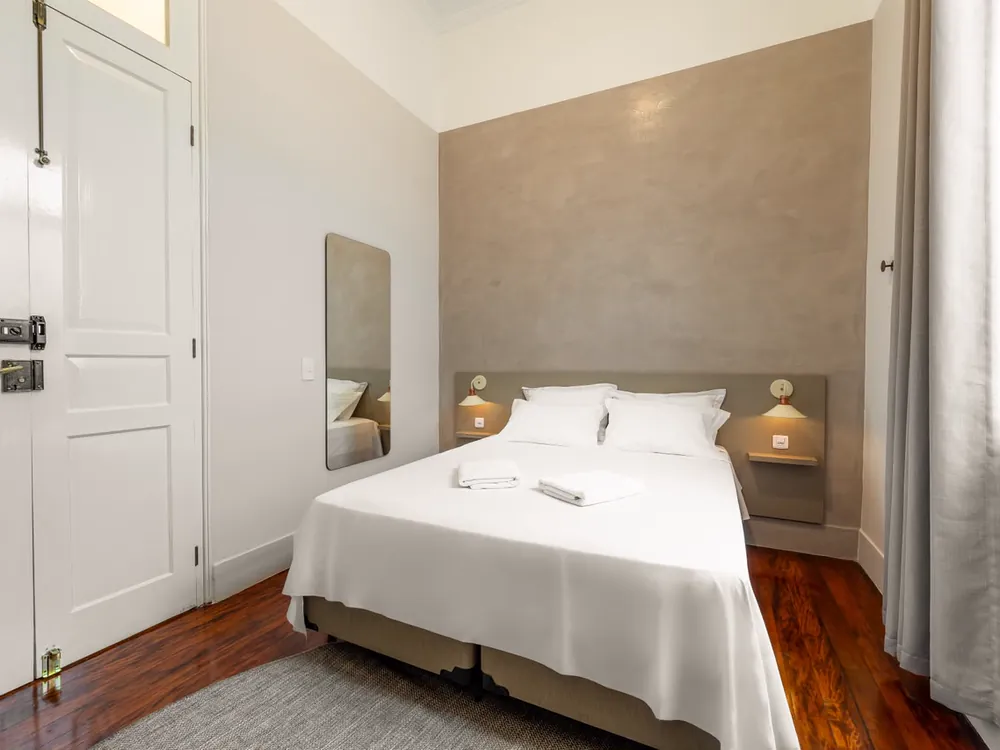 Quarto de casal com espelho alto e assoalho de madeira